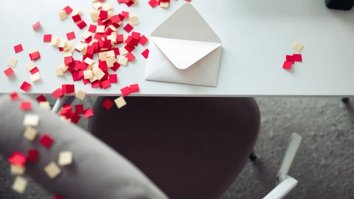 Un clavier et une tasse couverts de confettis, des collègues qui rient derrière